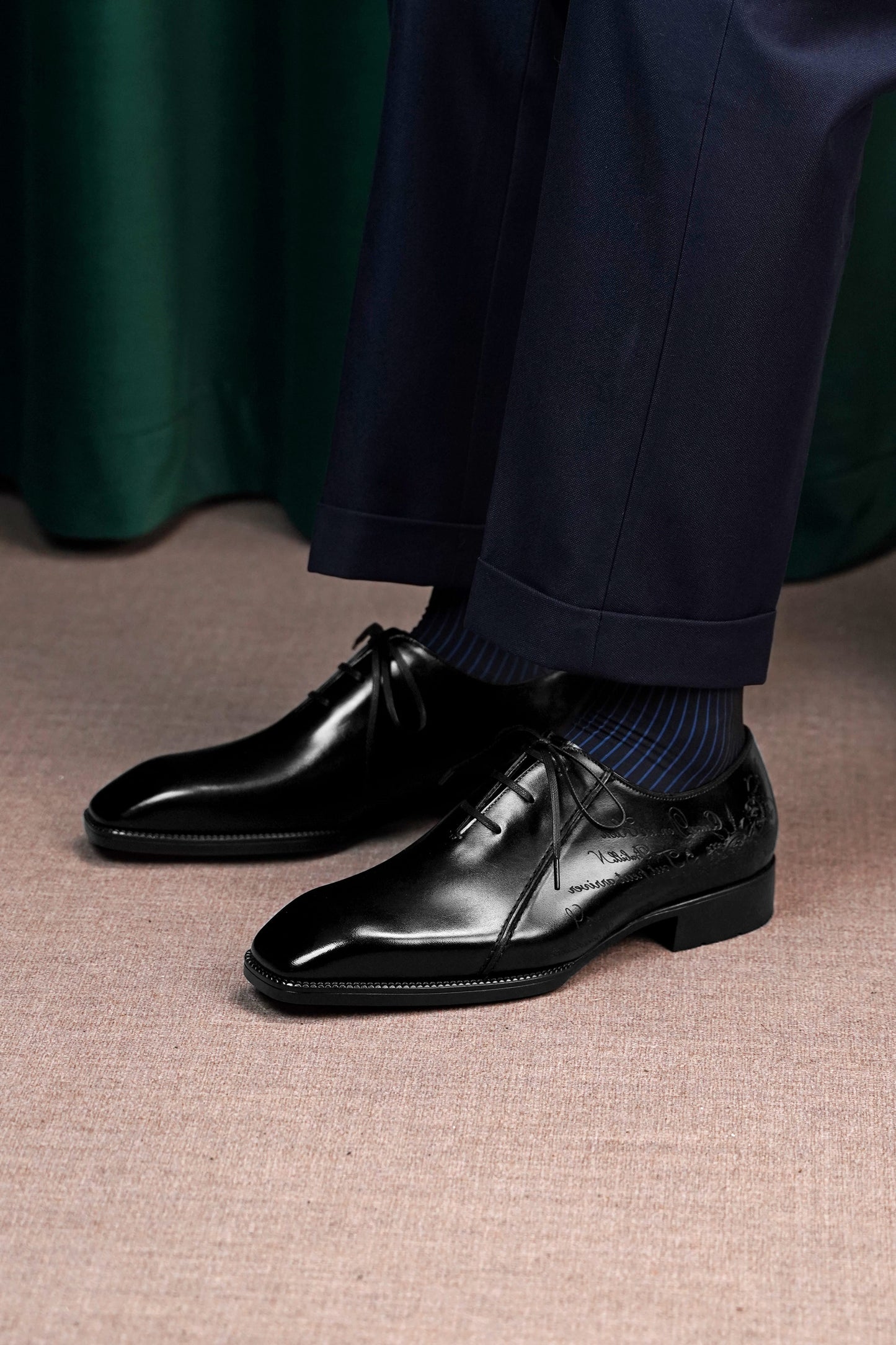 Men’s black leather Oxford dress shoes featuring a polished finish, lace-up closure, sleek pointed toe, and subtle embossed script detailing on the side panel.
