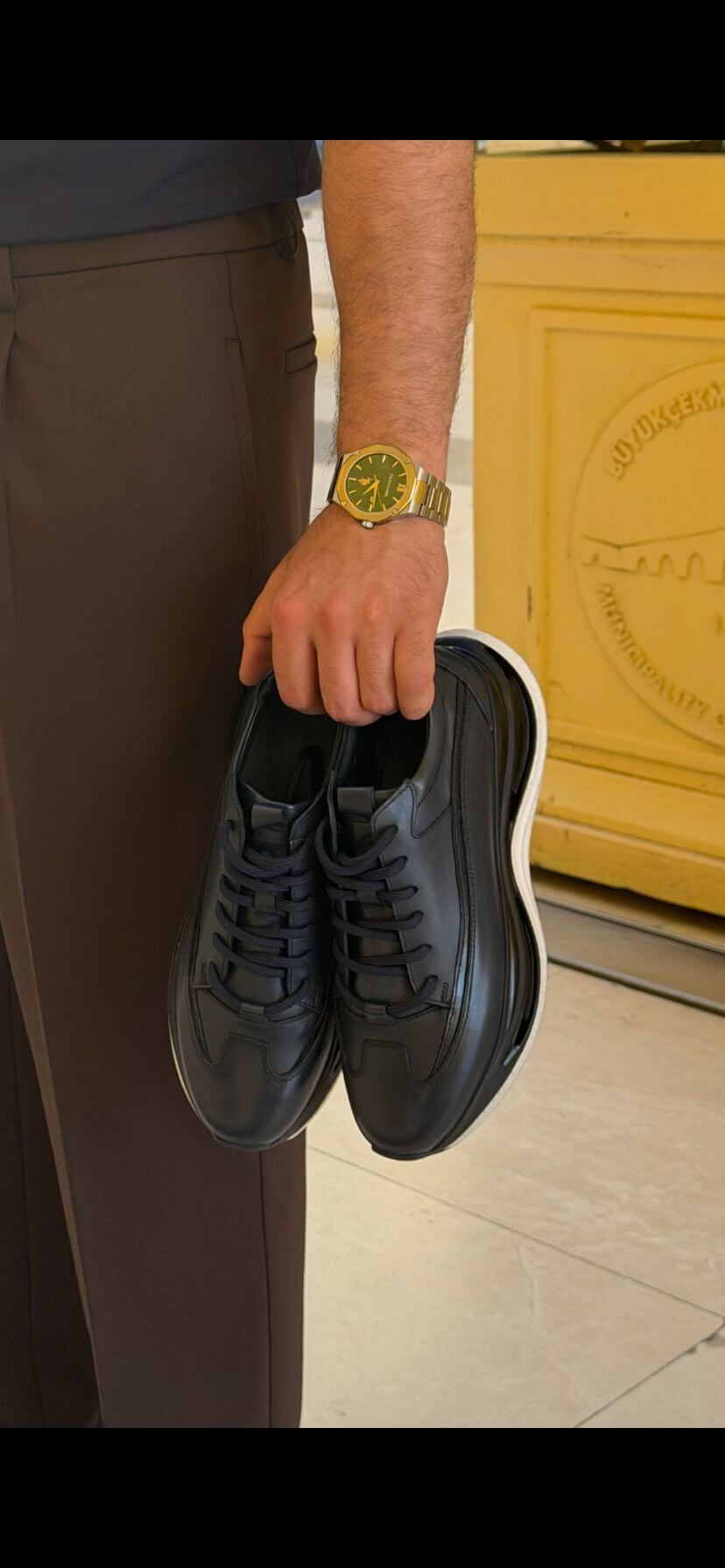 Men's black leather low-top sneaker front view showing clean low-profile silhouette