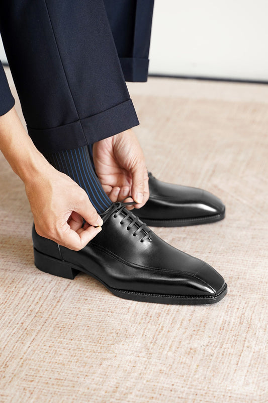Men’s black leather wholecut Oxford dress shoes with sleek lace-up design, polished finish, and elegant formal silhouette.