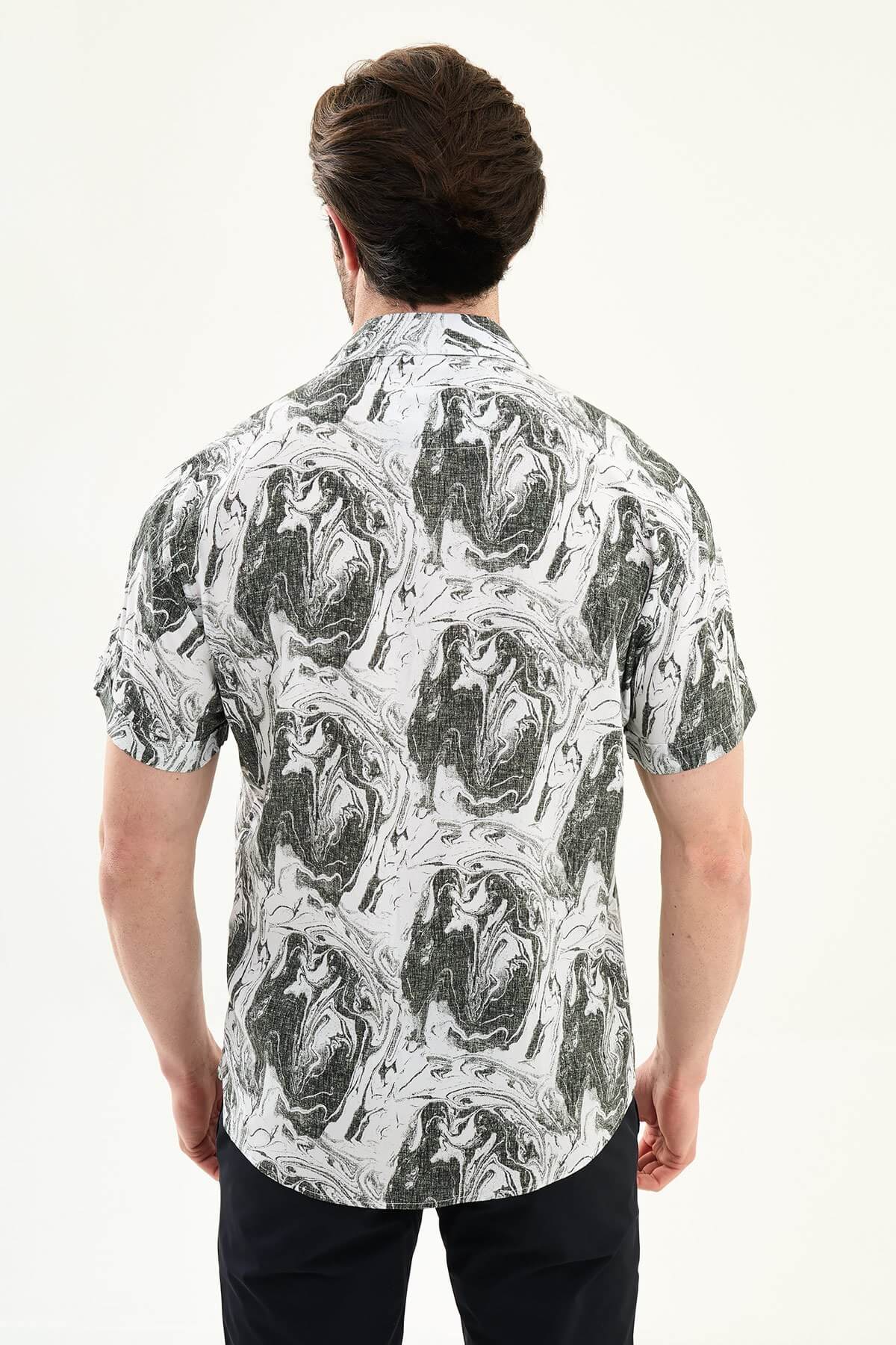 Male model wearing a black-and-white marble print short-sleeve slim fit shirt, styled with black pants, standing against a neutral background, showcasing summer casual fashion.