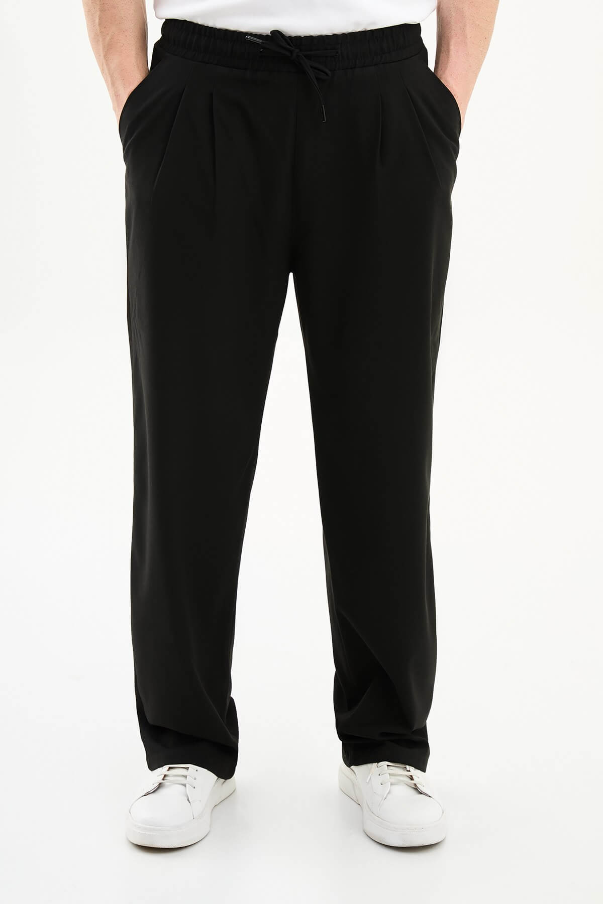 Men wearing black luxe drawstring jersey pants with white sneakers, styled for smart-casual summer occasions.