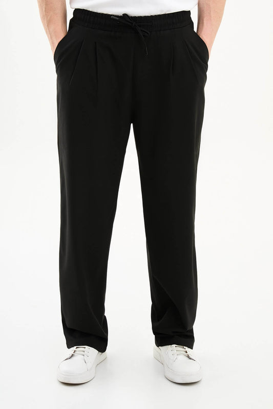 Men wearing black luxe drawstring jersey pants with white sneakers, styled for smart-casual summer occasions.
