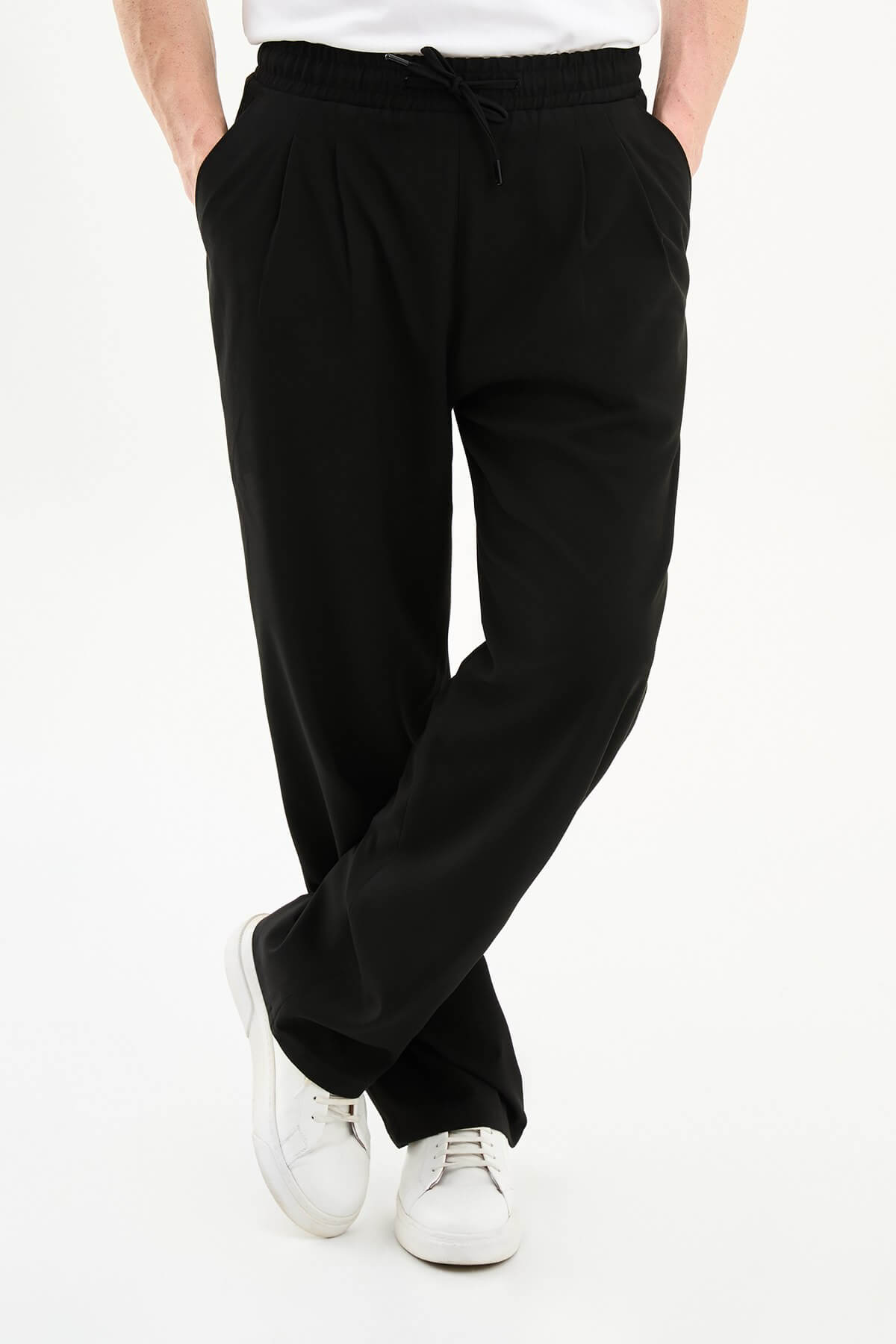 Men wearing black luxe drawstring jersey pants with white sneakers, styled for smart-casual summer occasions.