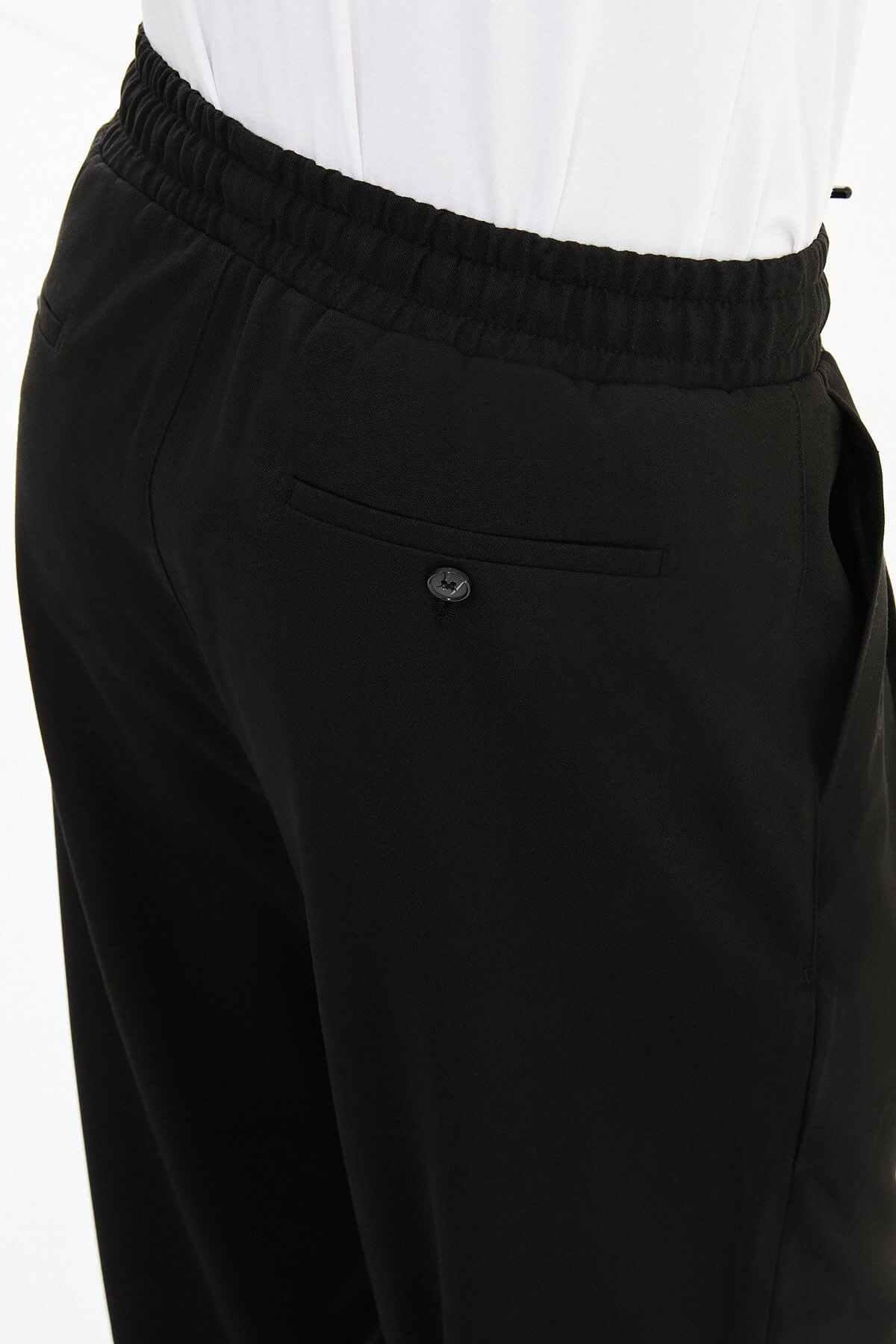Men wearing black luxe drawstring jersey pants with white sneakers, styled for smart-casual summer occasions.