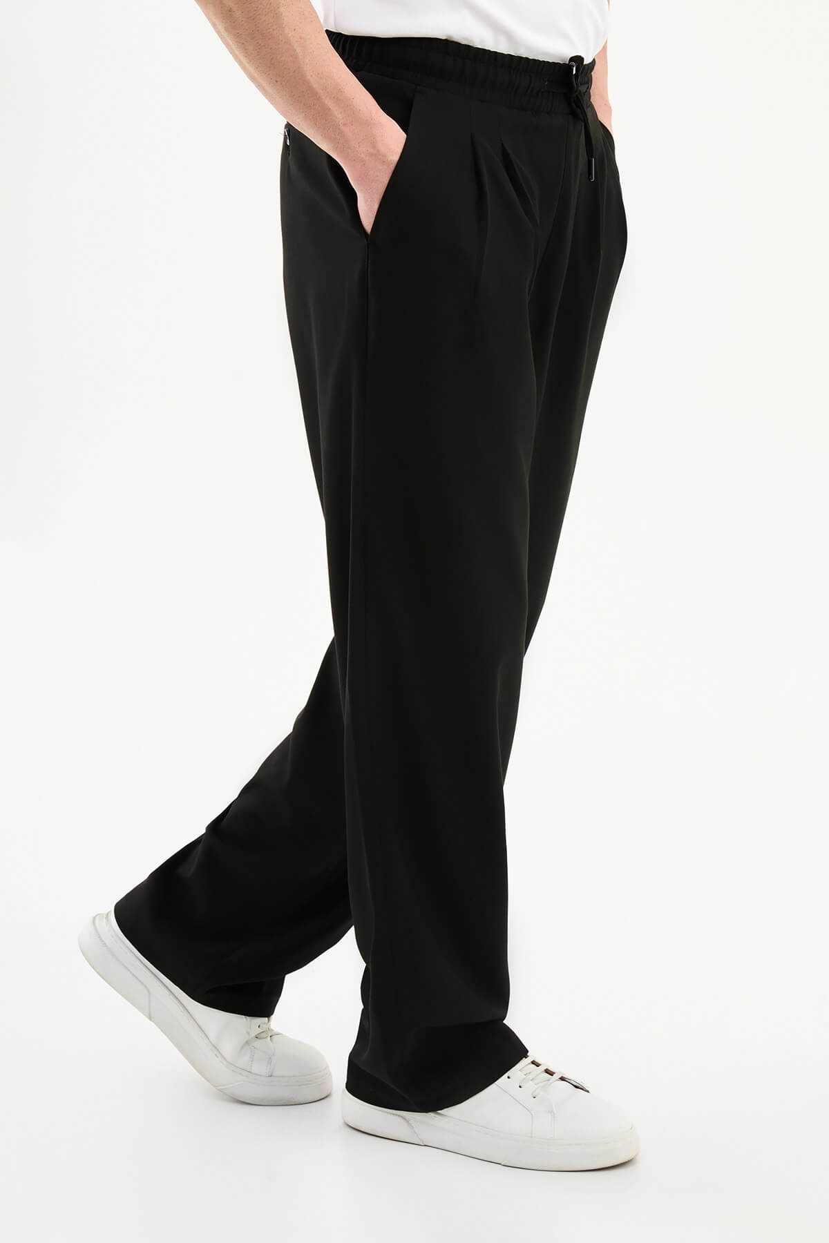 Men wearing black luxe drawstring jersey pants with white sneakers, styled for smart-casual summer occasions.