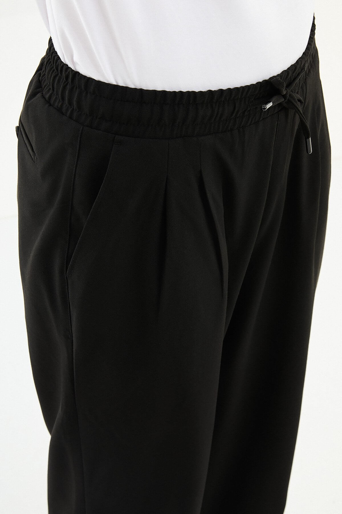Men wearing black luxe drawstring jersey pants with white sneakers, styled for smart-casual summer occasions.