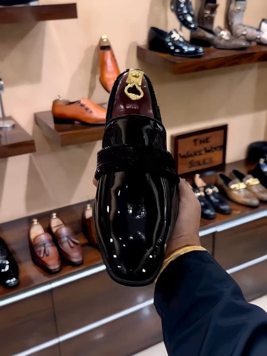 Black patent leather loafers with a glossy finish and woven strap detail, styled for both formal and semi-formal occasions.