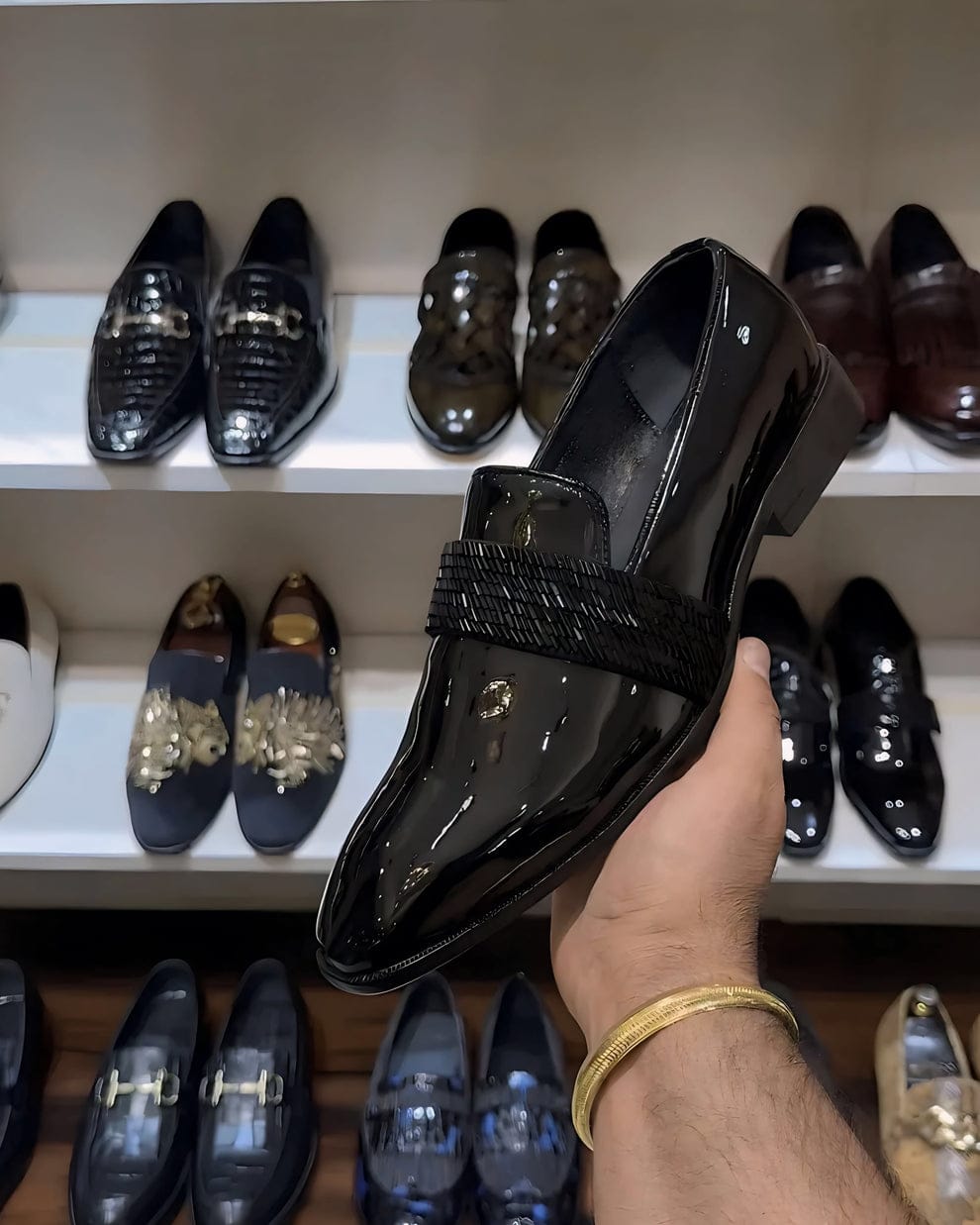 Black patent leather loafers with a glossy finish and woven strap detail, styled for both formal and semi-formal occasions.