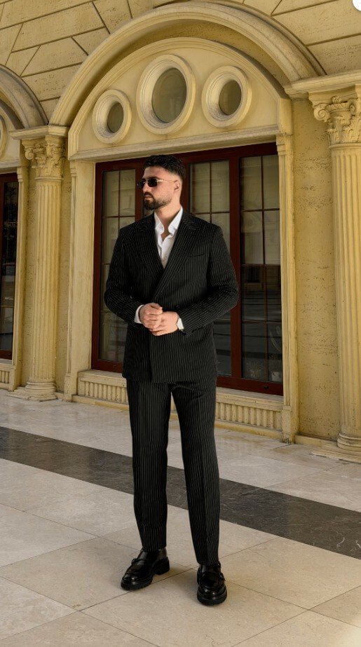 Black pinstripe double-breasted men’s suit styled with black loafers