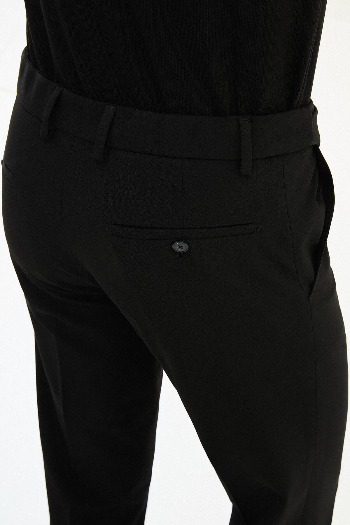 Man wearing black slim-fit formal trousers paired with a black knit shirt and black leather shoes.