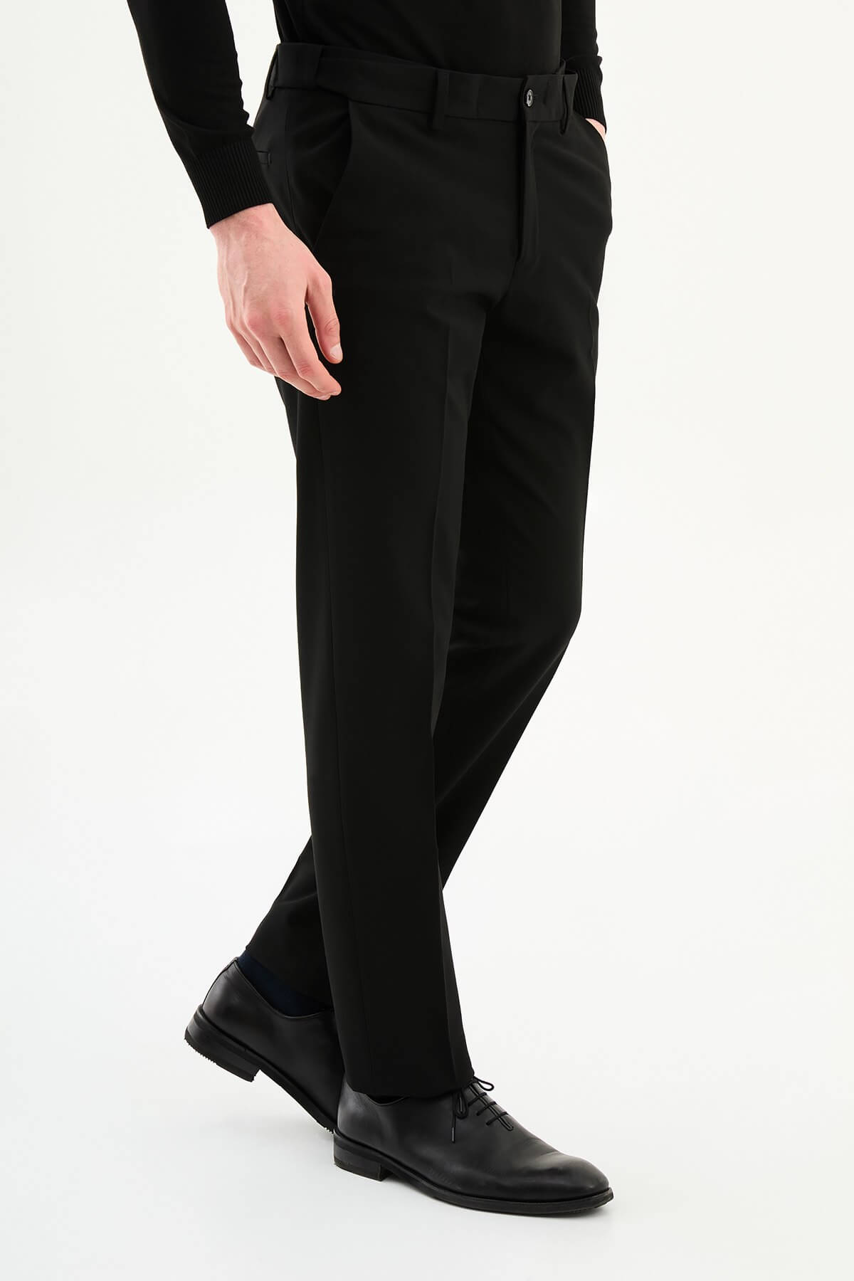 Man wearing black slim-fit formal trousers paired with a black knit shirt and black leather shoes.