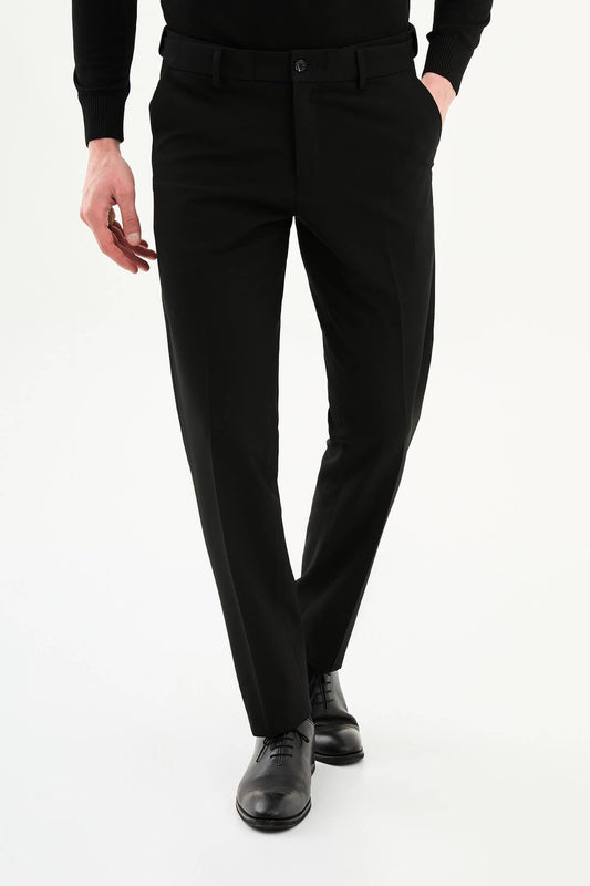 Man wearing black slim-fit formal trousers paired with a black knit shirt and black leather shoes.