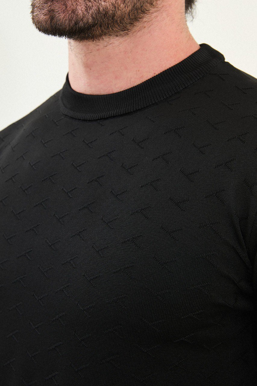 Men’s slim-fit black crew-neck sweater with geometric ‘T’ textured knit front panel, cotton-viscose-elastane blend, styled with charcoal gray denim in a monochrome winter outfit.