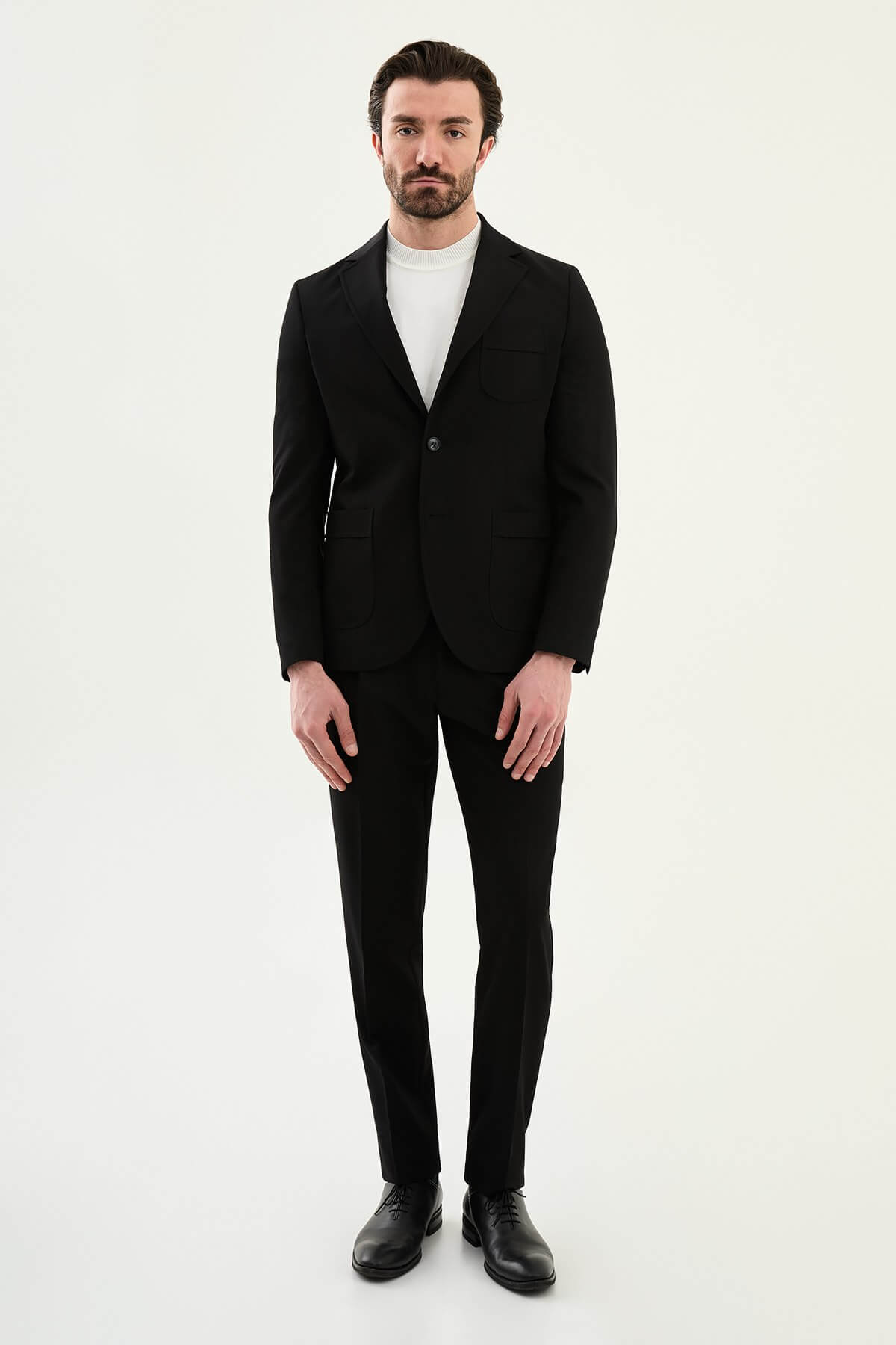 Close-up of a men's black slim fit single-breasted blazer with notched lapels and front pockets, styled over a white shirt for a modern formal look.