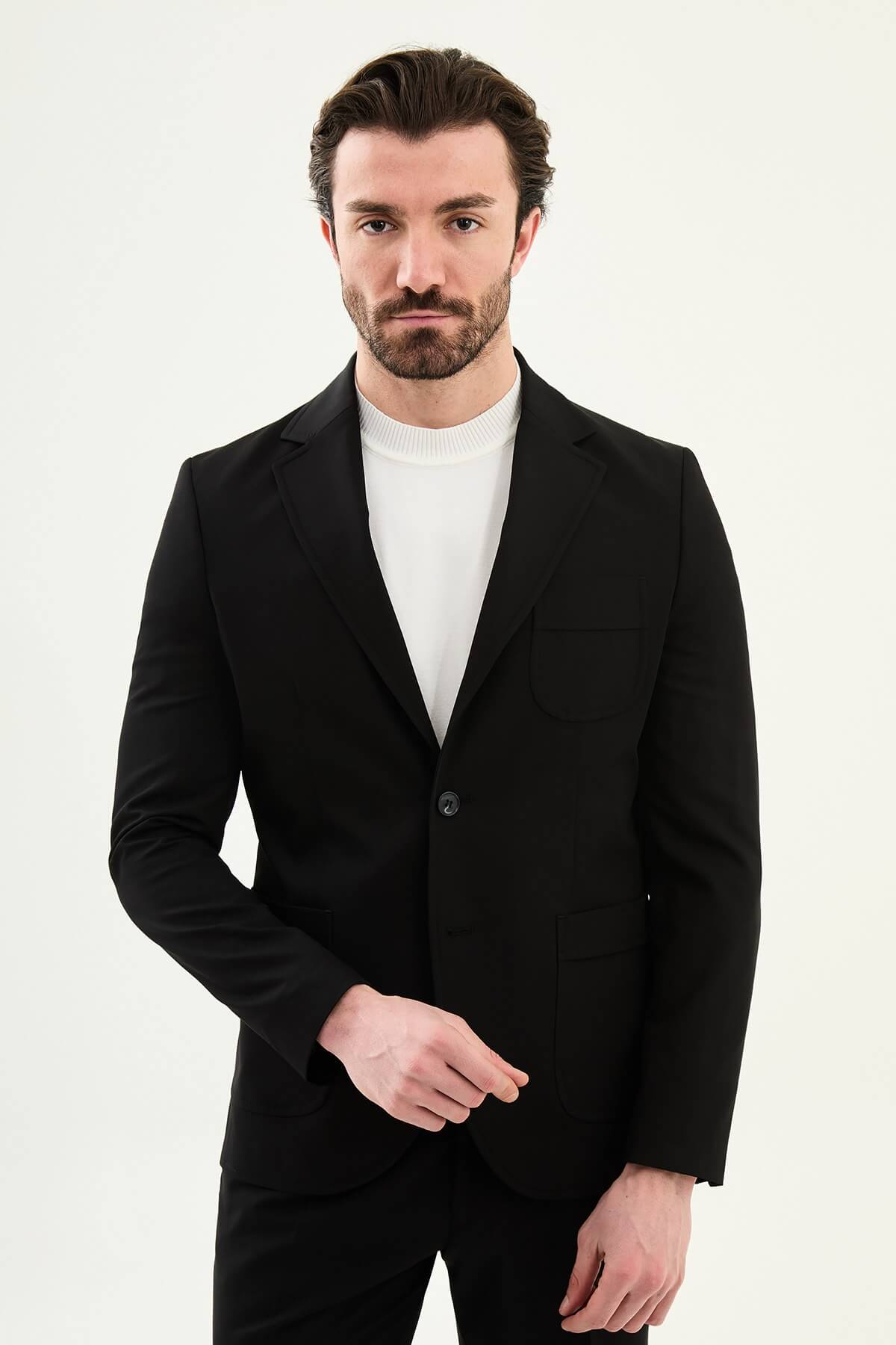 Close-up of a men's black slim fit single-breasted blazer with notched lapels and front pockets, styled over a white shirt for a modern formal look.