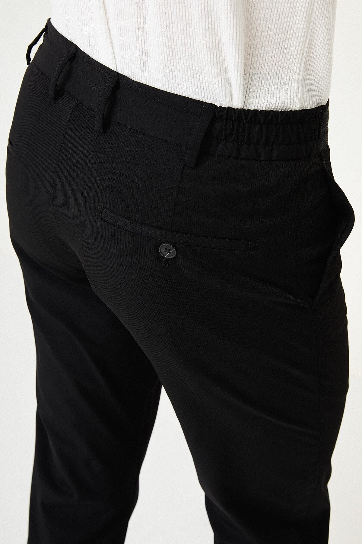 Man wearing black slim-fit summer trousers styled with a white polo shirt and black loafers.