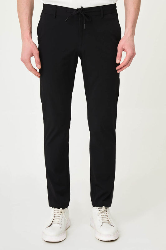 Man wearing black slim-fit summer trousers styled with a white polo shirt and black loafers.