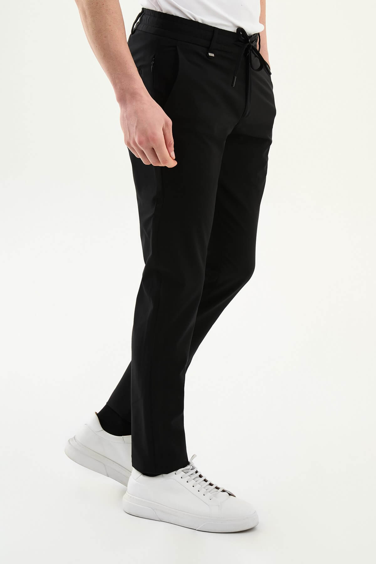 Man wearing black slim-fit summer trousers styled with white sneakers and a light summer top.