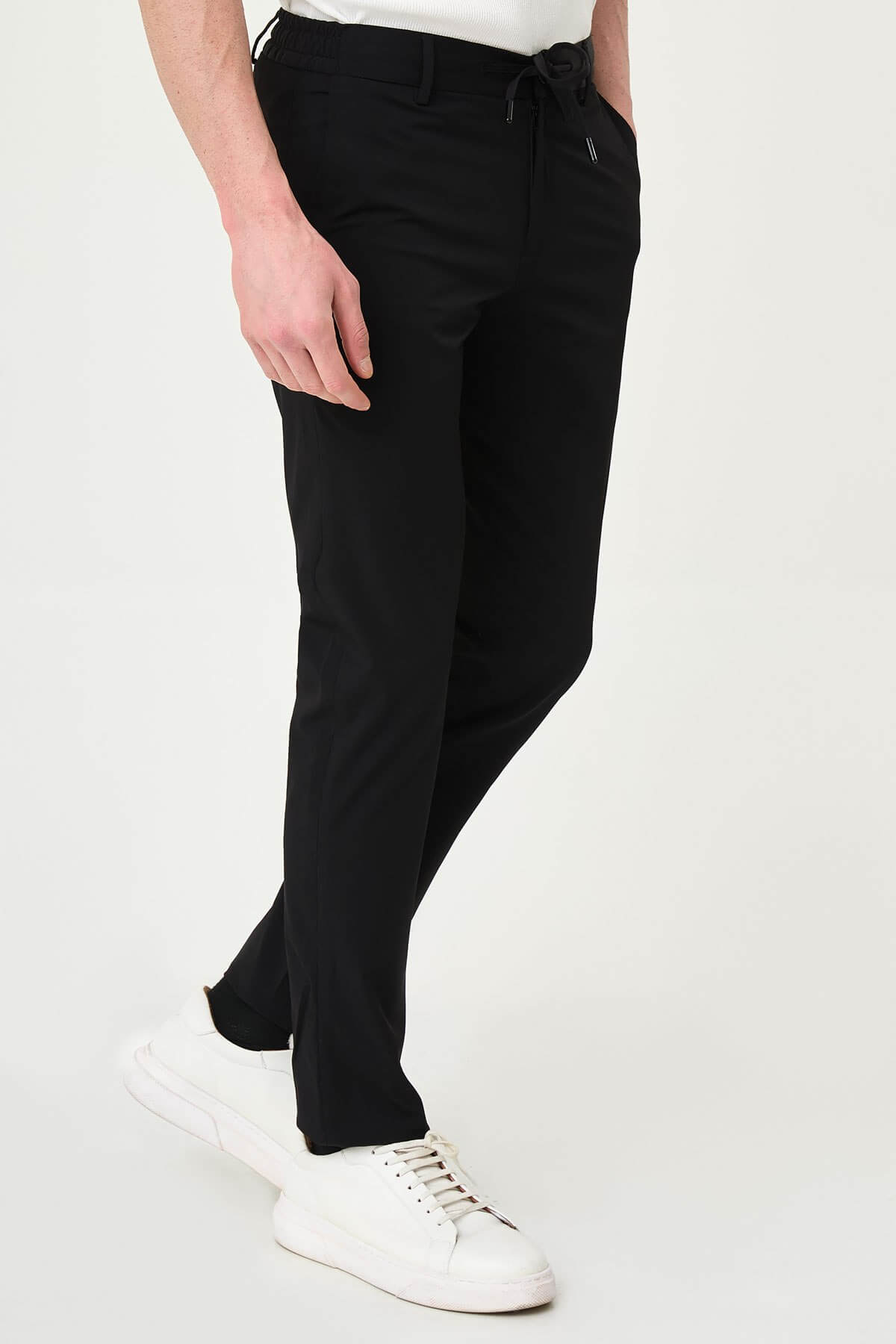 Man wearing black slim-fit summer trousers styled with a white polo shirt and black loafers.