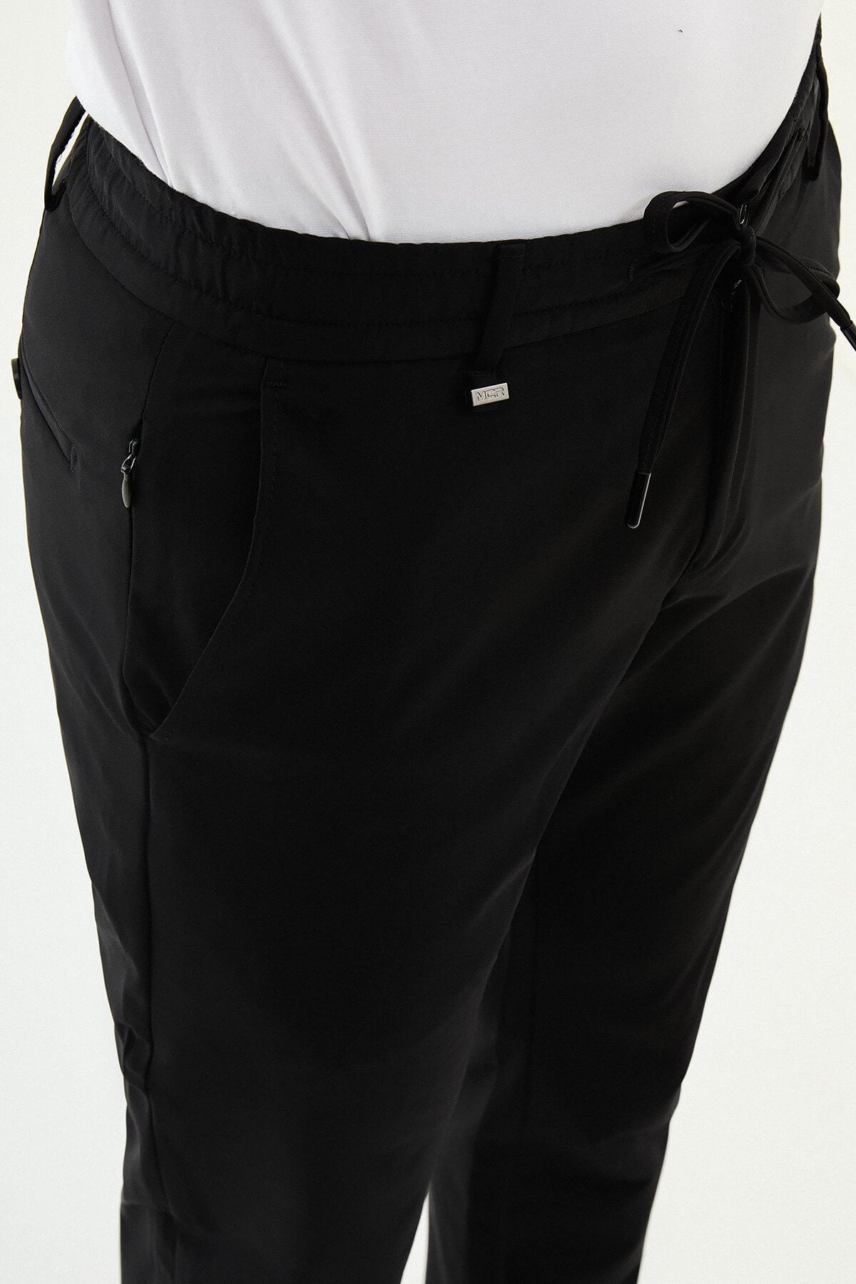 Man wearing black slim-fit summer trousers styled with white sneakers and a light summer top.