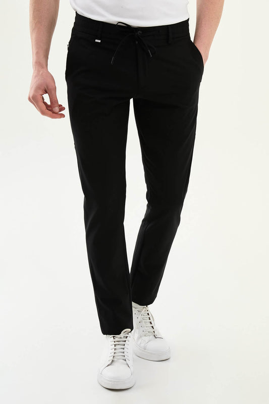 Man wearing black slim-fit summer trousers styled with white sneakers and a light summer top.
