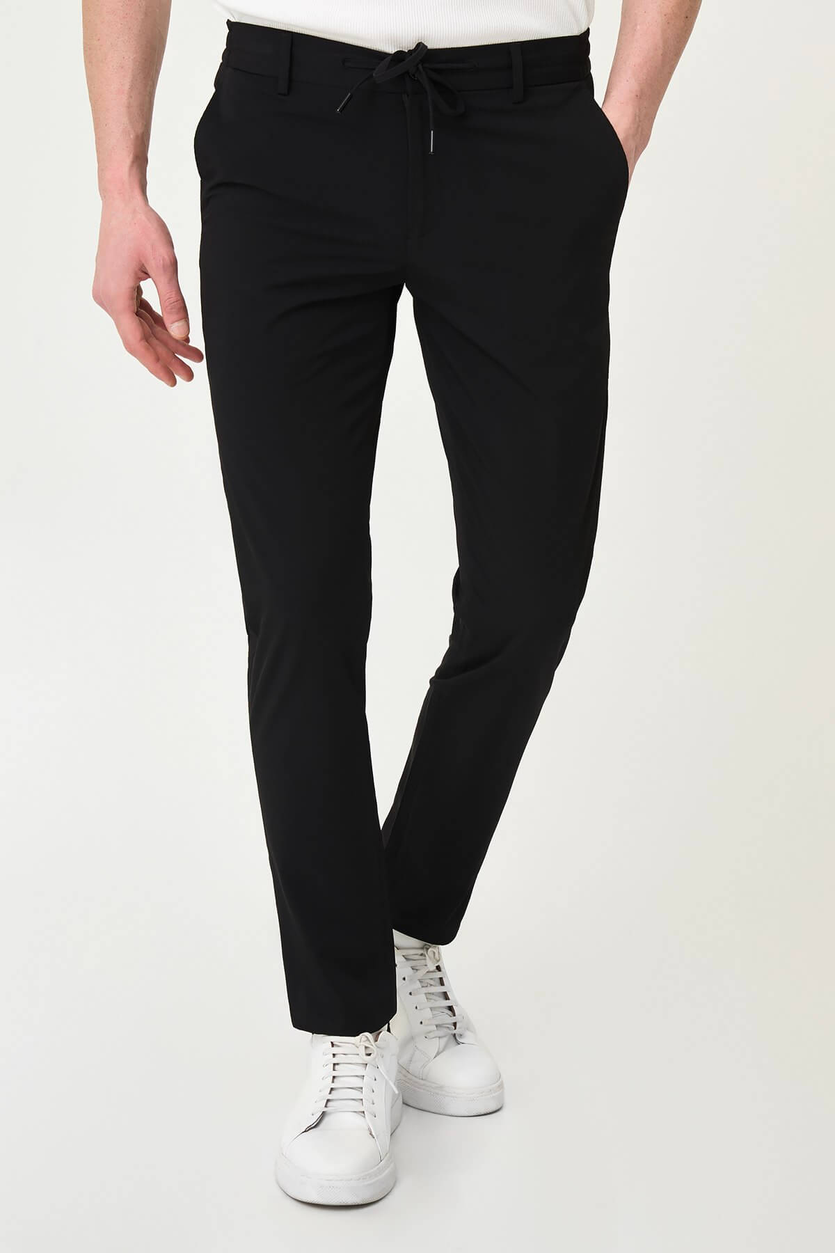 Man wearing black slim-fit summer trousers styled with a white polo shirt and black loafers.