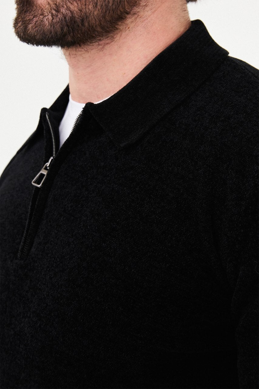 Men’s black polo neck knit sweater with zip collar detail styled with grey trousers for a refined fall winter smart-casual outfit.
