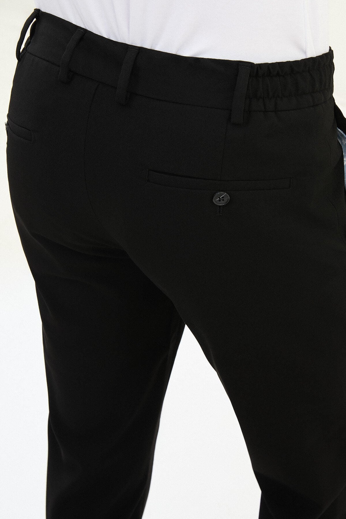 Men wearing black slim-fit drawstring trousers with elastic waistband, casual-formal hybrid, styled with dress shoes and sneakers for versatile summer menswear.