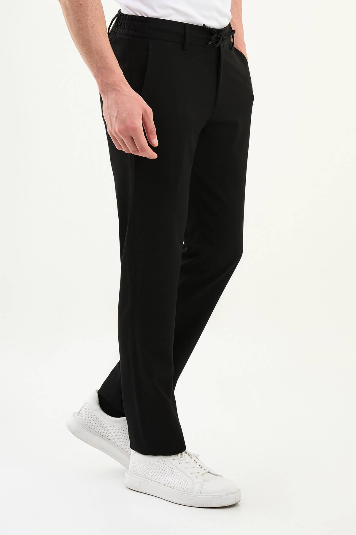 Men wearing black slim-fit drawstring trousers with elastic waistband, casual-formal hybrid, styled with dress shoes and sneakers for versatile summer menswear.