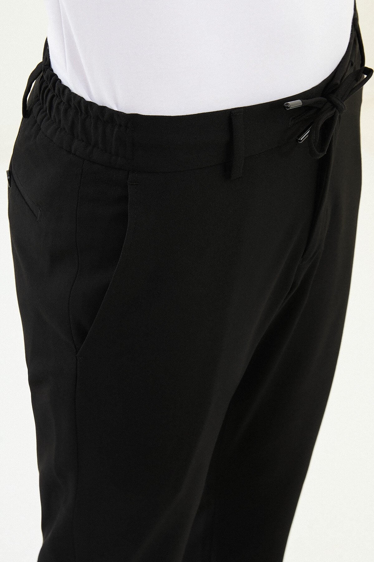 Men wearing black slim-fit drawstring trousers with elastic waistband, casual-formal hybrid, styled with dress shoes and sneakers for versatile summer menswear.