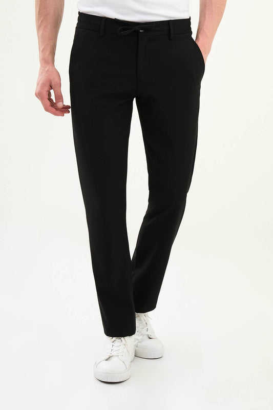 Men wearing black slim-fit drawstring trousers with elastic waistband, casual-formal hybrid, styled with dress shoes and sneakers for versatile summer menswear.