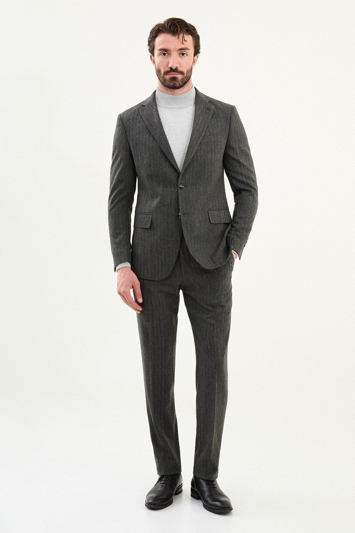 Men’s gray herringbone slim-fit suit with structured shoulders and tailored waist, high-wool blend fabric with stretch for winter wear, styled with a light gray fine-gauge turtleneck