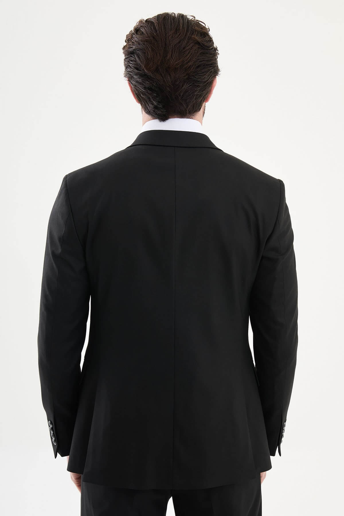 man wearing a black slim-fit three-piece suit, including blazer, waistcoat, and trousers, styled with a white dress shirt and black tie, suitable for formal events or weddings.