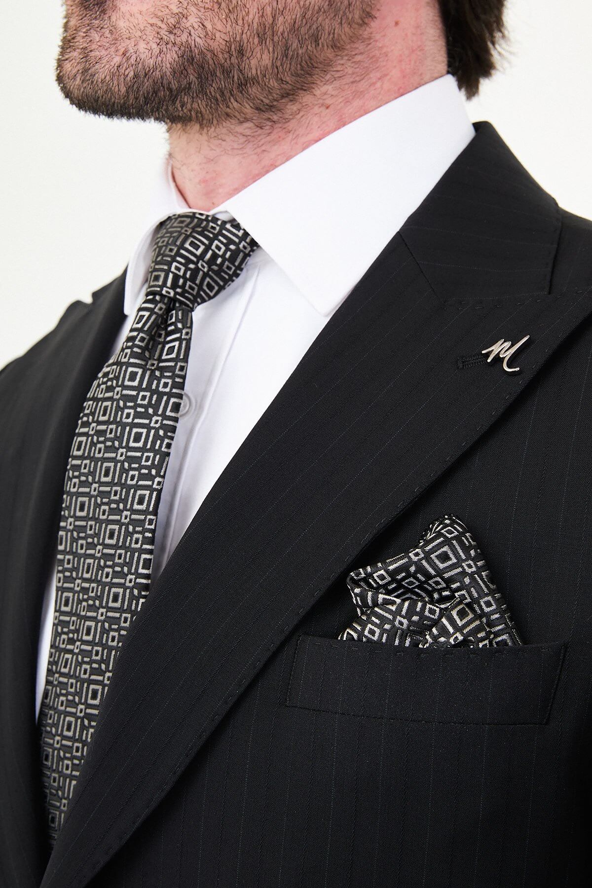 Man wearing a black slim fit wide collar premium wool suit with a patterned tie and pocket square