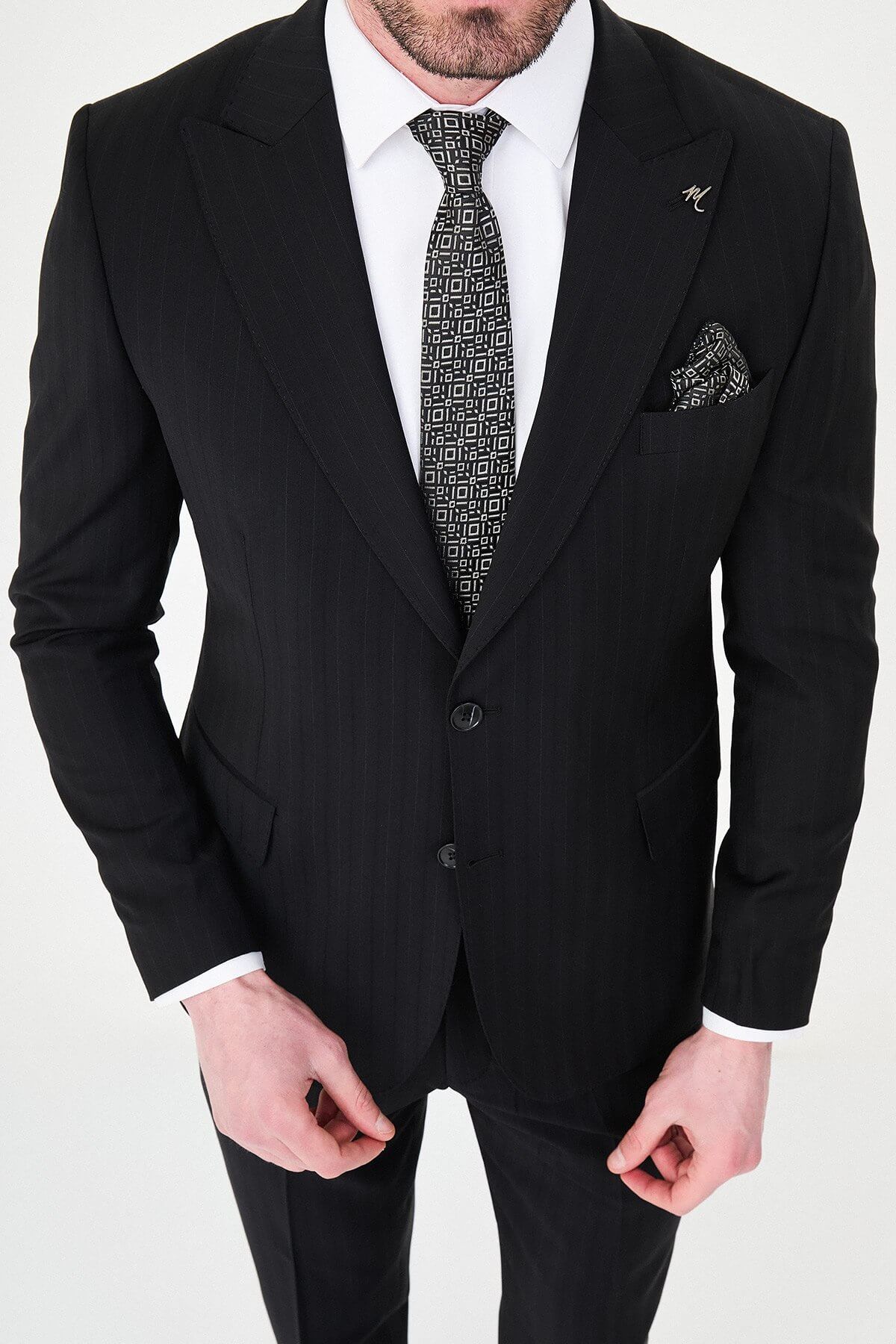 Man wearing a black slim fit wide collar premium wool suit with a patterned tie and pocket square