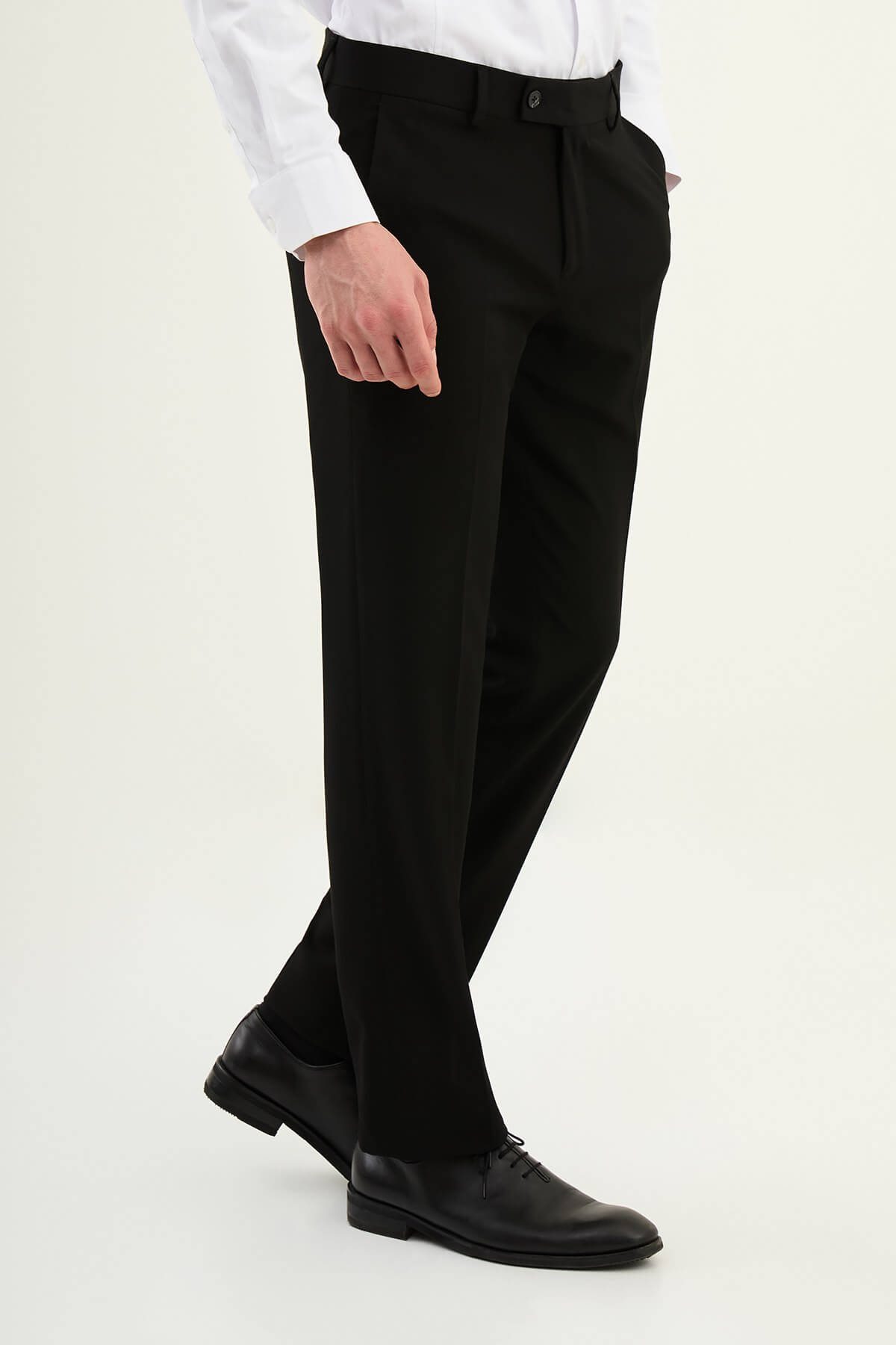 Black slim-fit formal trousers with front pleats, styled with black leather shoes.