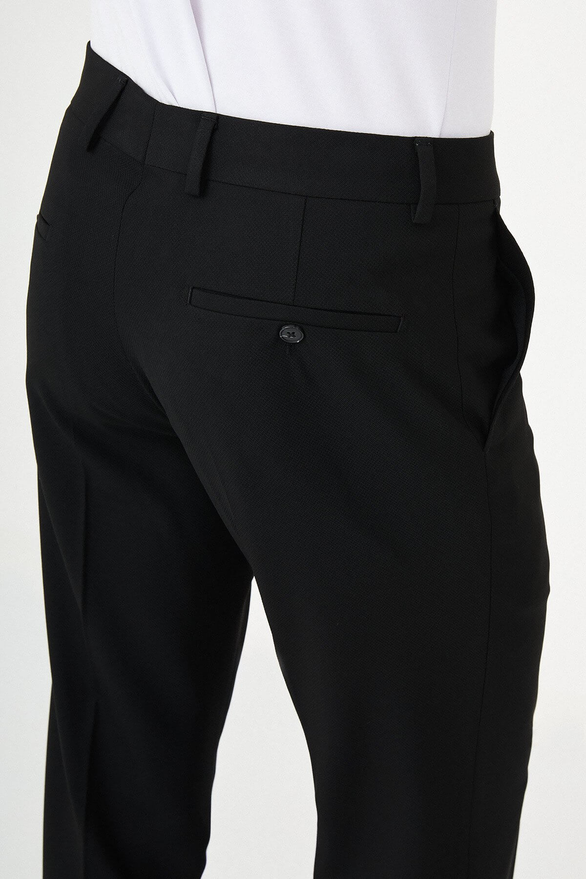 Man wearing black pleated dress trousers with straight slim fit, styled with a white dress shirt and black leather shoes.