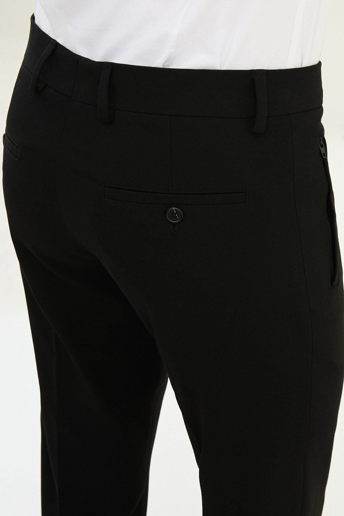 Man wearing black slim-fit dress trousers styled with a white shirt and black leather shoes.