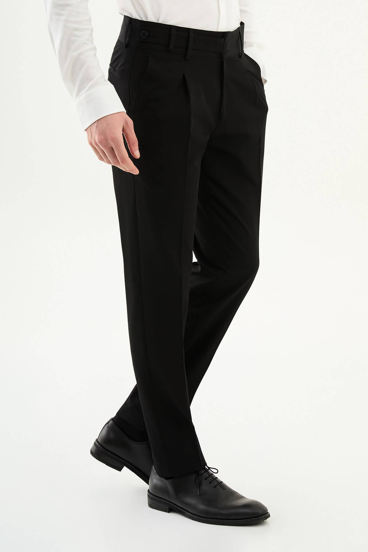 Man wearing black slim-fit straight-leg pleated trousers styled with a white dress shirt and black leather shoes, ideal for summer formal and business occasions.