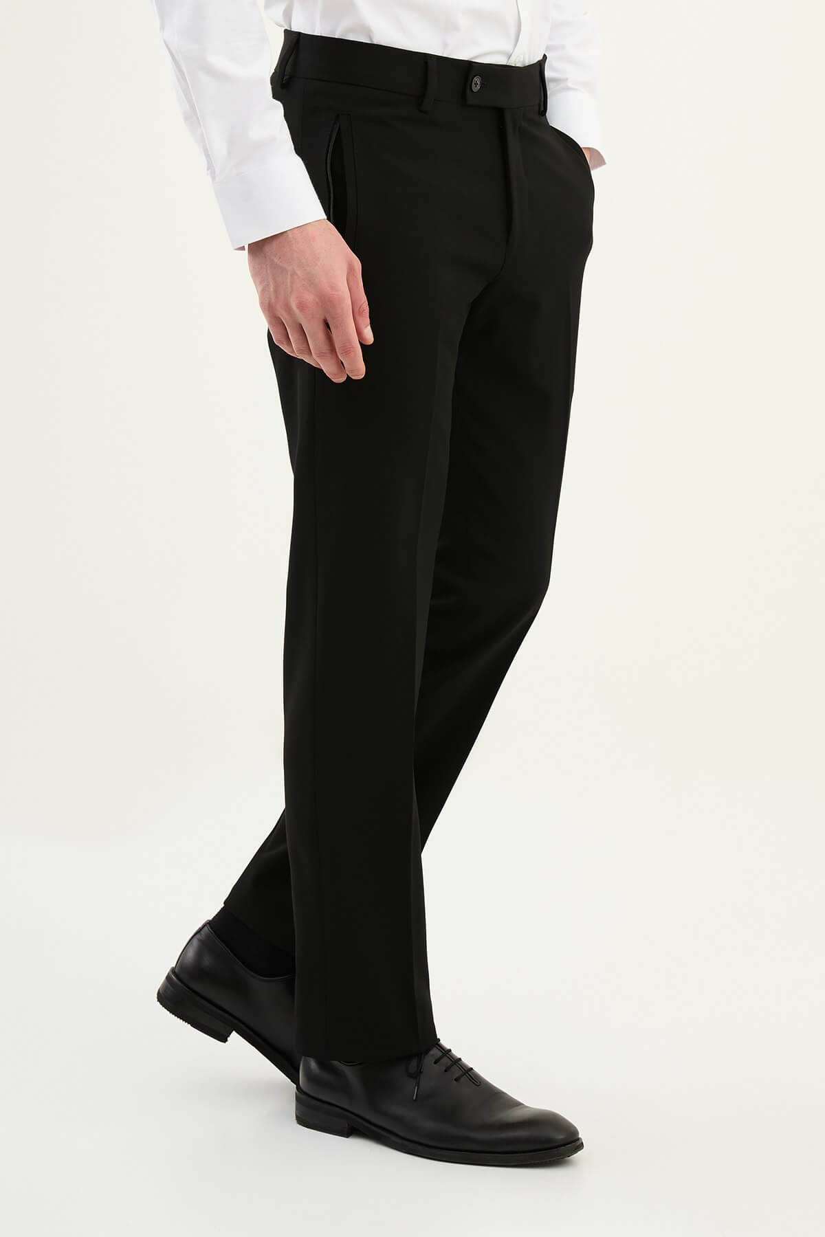 Man wearing black slim-fit dress trousers styled with a white shirt and black leather shoes.