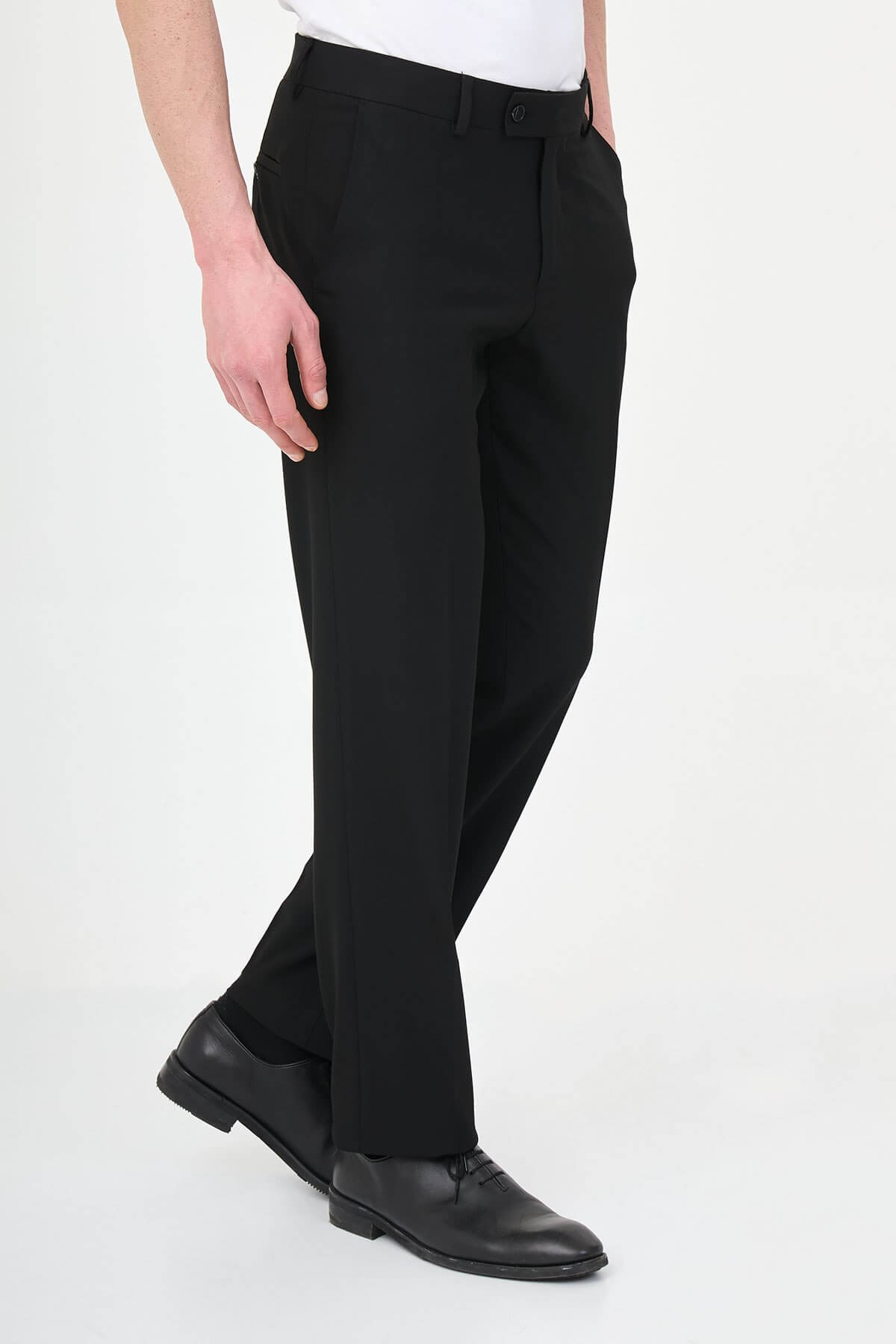 Man wearing black pleated dress trousers with straight slim fit, styled with a white dress shirt and black leather shoes.