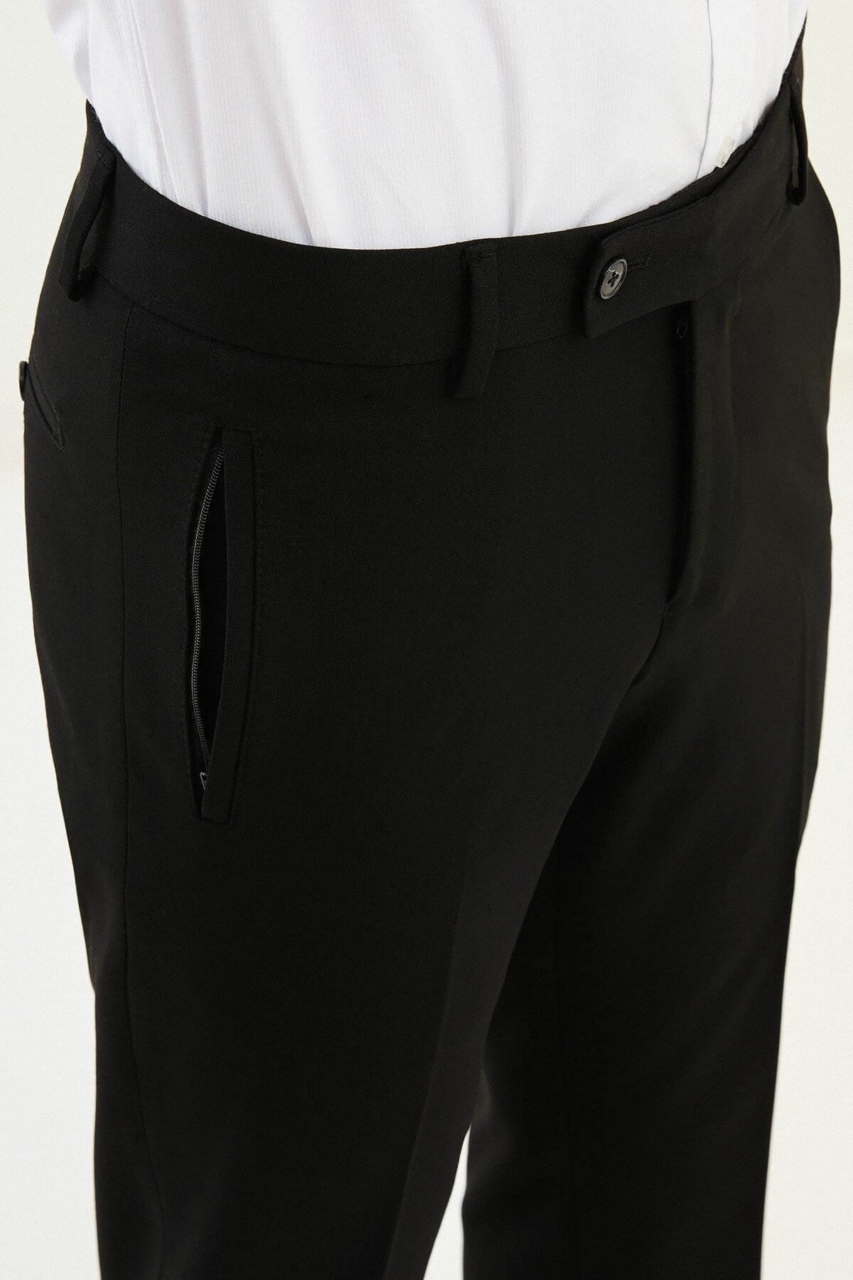 Man wearing black slim-fit dress trousers styled with a white shirt and black leather shoes.