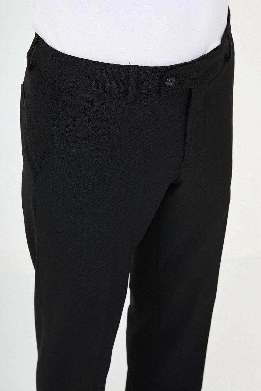 Man wearing black pleated dress trousers with straight slim fit, styled with a white dress shirt and black leather shoes.