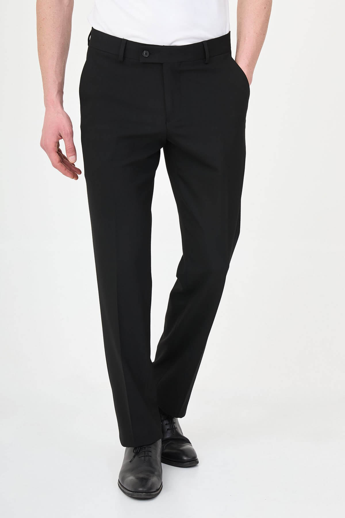 Man wearing black pleated dress trousers with straight slim fit, styled with a white dress shirt and black leather shoes.