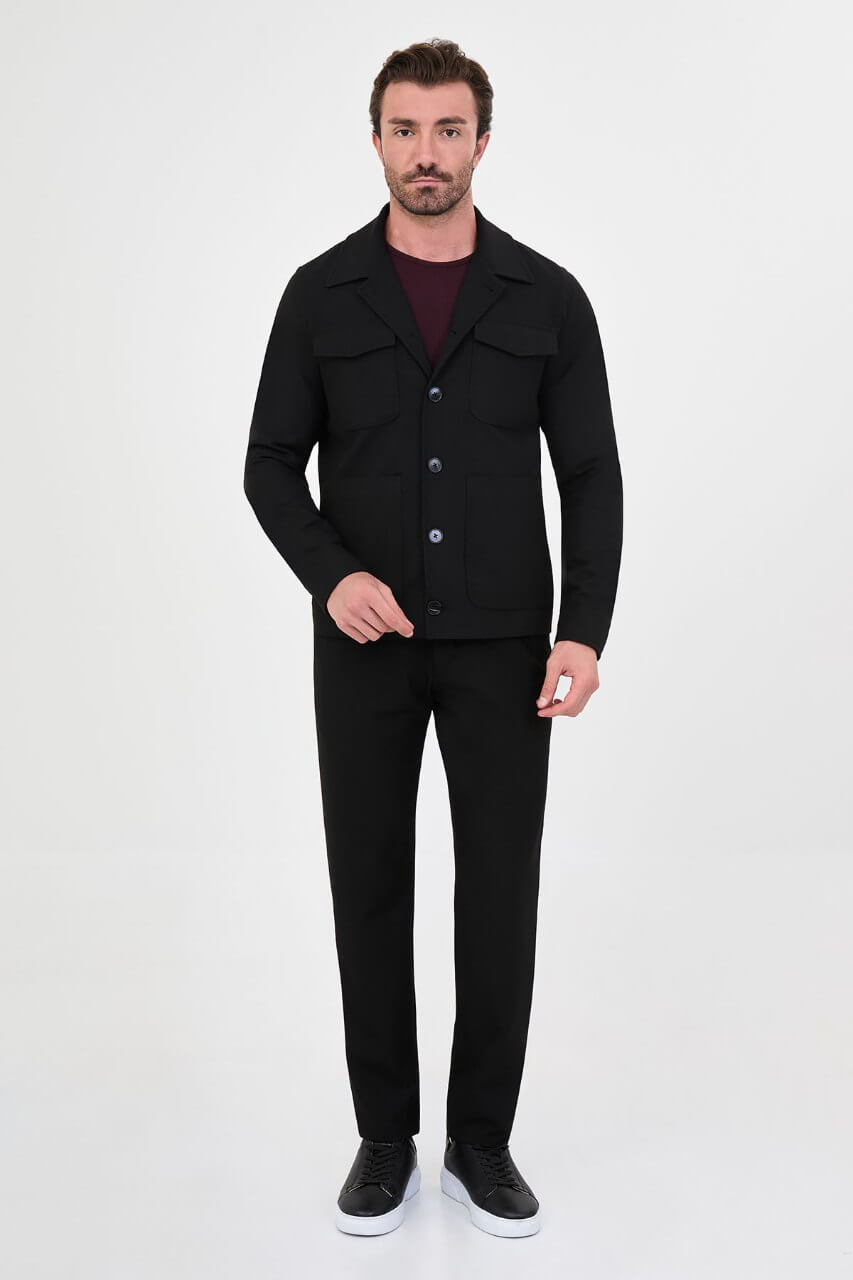 Men's black fall/winter utility jacket styled with a burgundy crew-neck shirt and black trousers.