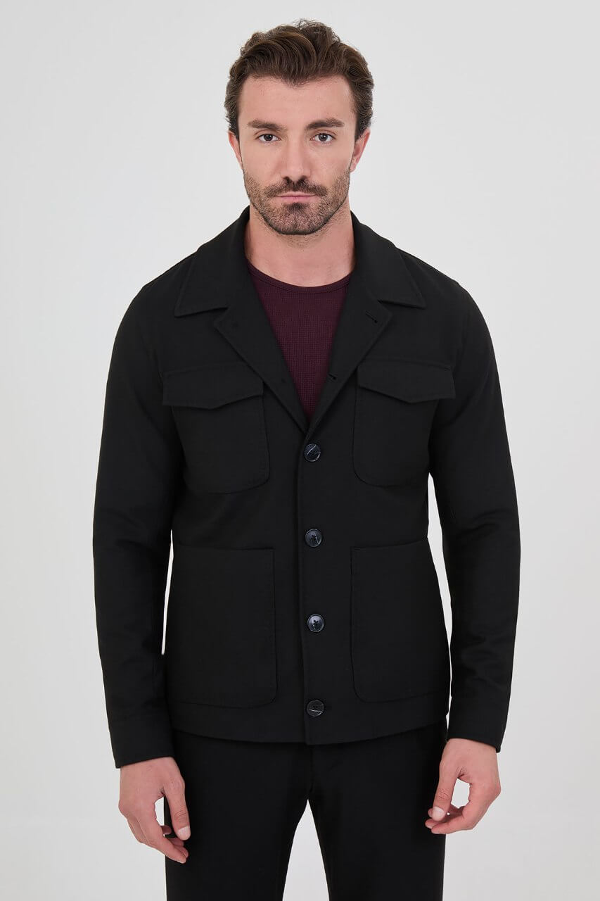 Men's black fall/winter utility jacket styled with a burgundy crew-neck shirt and black trousers.