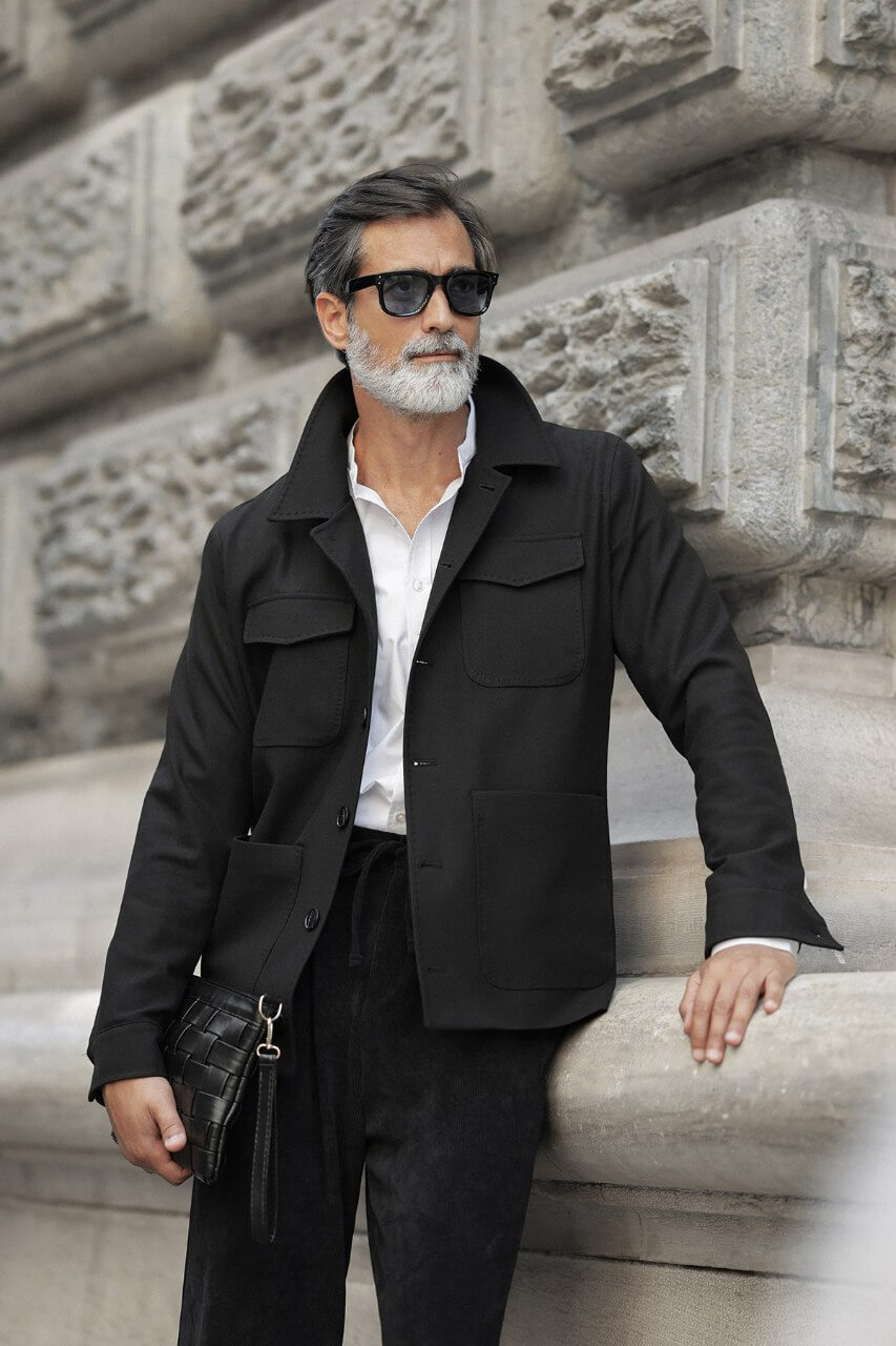 Men's black fall/winter utility jacket styled with a burgundy crew-neck shirt and black trousers.