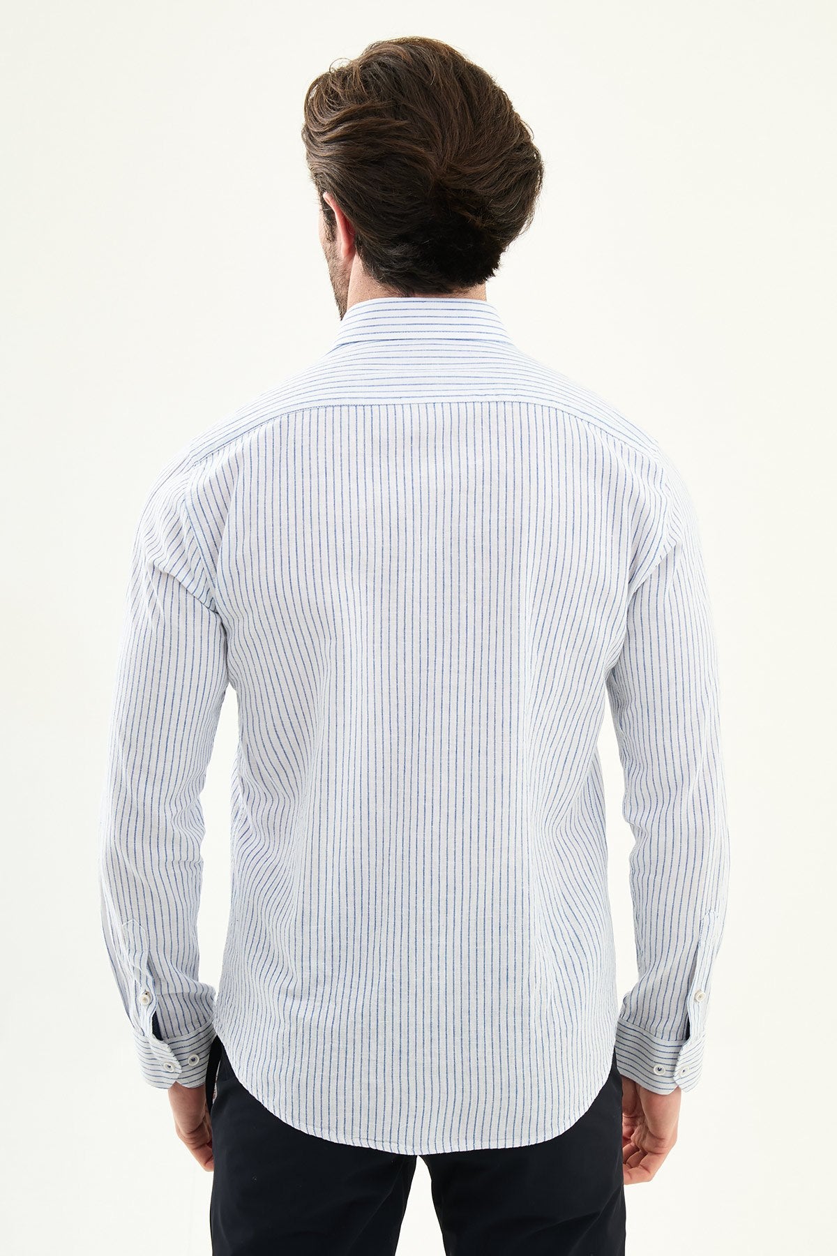 blue slim-fit long sleeve shirt with a contrasting pocket detail, standing indoors against a neutral backdrop