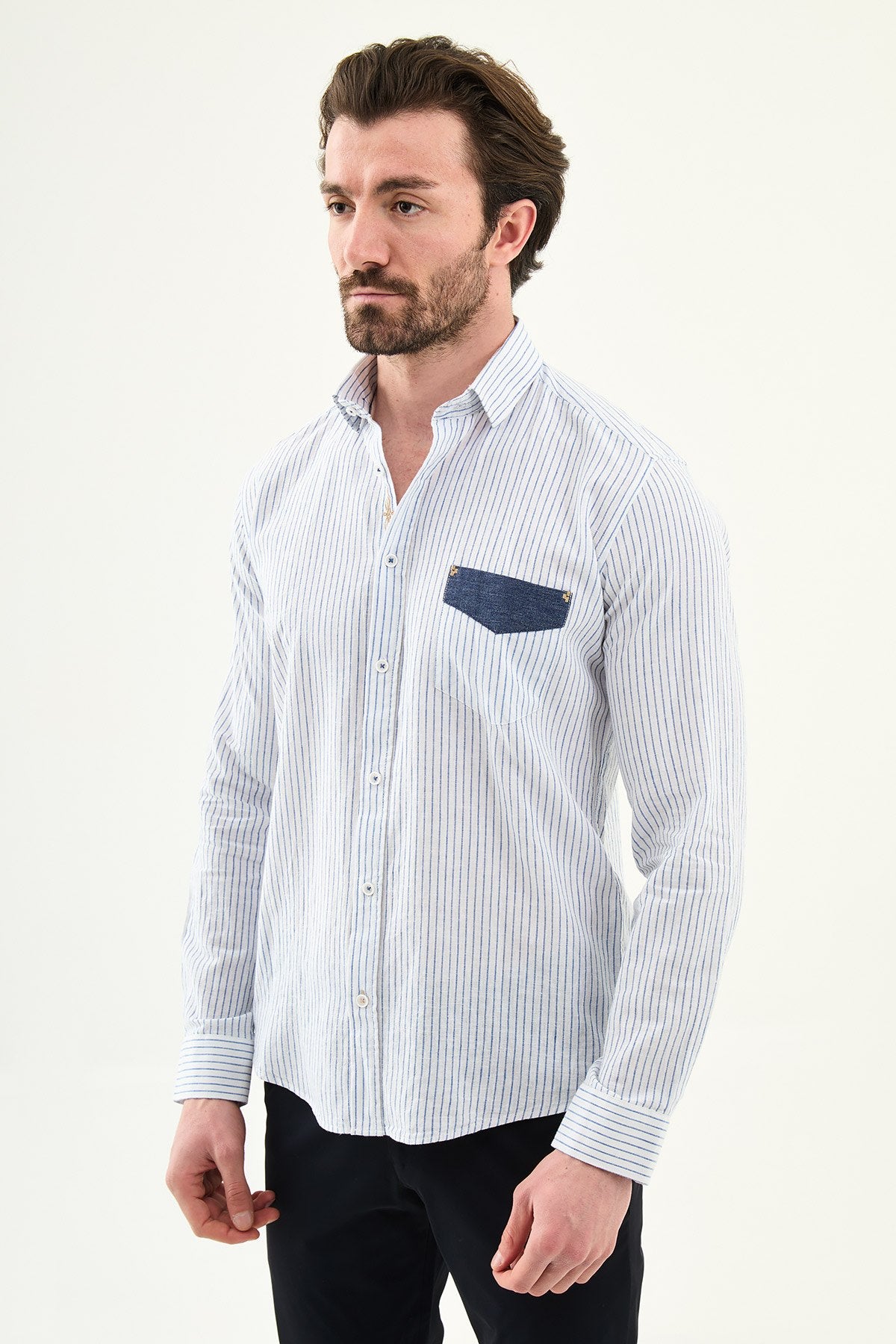blue slim-fit long sleeve shirt with a contrasting pocket detail, standing indoors against a neutral backdrop