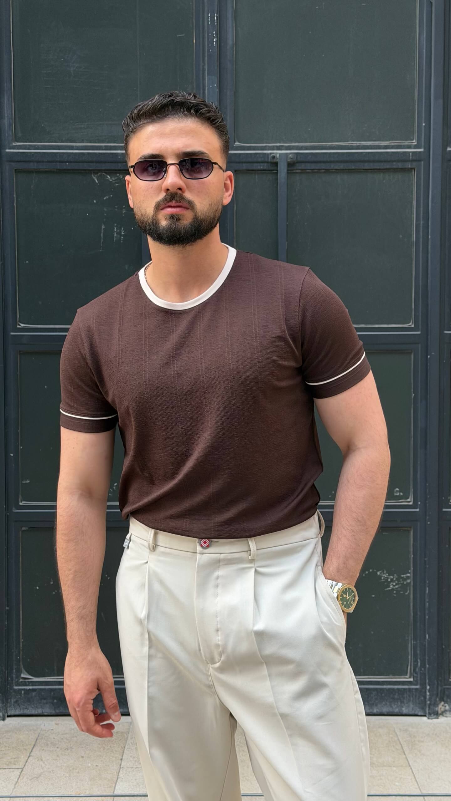 brown crew neck T-shirt with subtle texture, worn by a male model, paired with cream trousers, showcasing a slim fit and short sleeves.